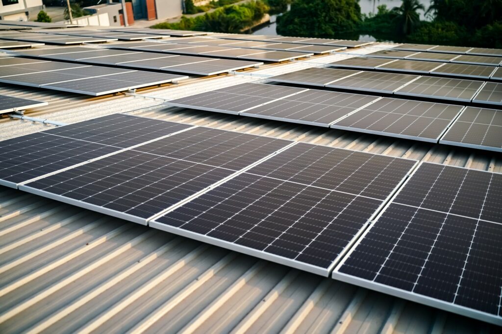 Solar panel installer installing solar panels on roof of warehouse